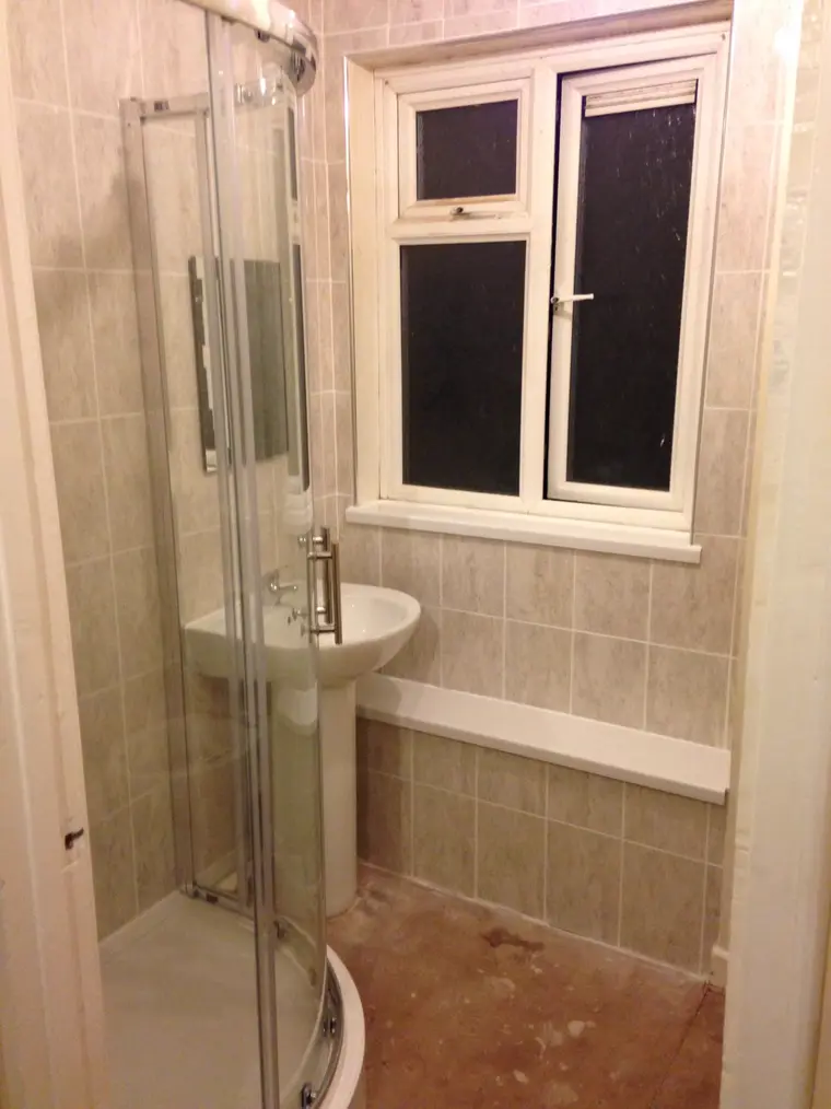 Quadrant shower enclosure and pedestal basin with cream wall tiles